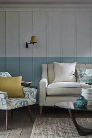 Blue and white living room with wall paneling and white linen couch with blue and yellow ochre detailing by Vanessa Arbuthnott