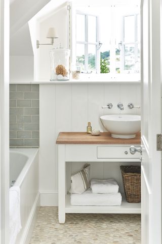 Modern, white, bright bathroom with green/grey tiles behind the bath