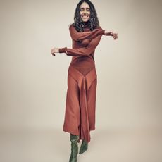 A female model wearing a rust-pink coloured satin dress from The Outnet.