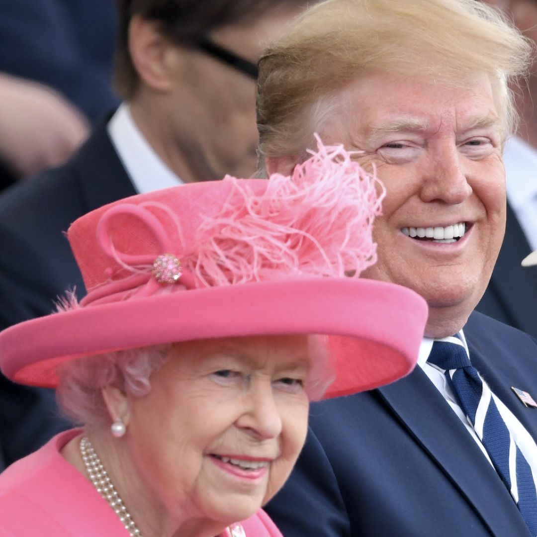 Queen Elizabeth wears a bright pink dress and matching hat with pearl earrings and a pearl necklace as Donald Trump sits beside her wearing a navy suit with his fluffy blonde hair