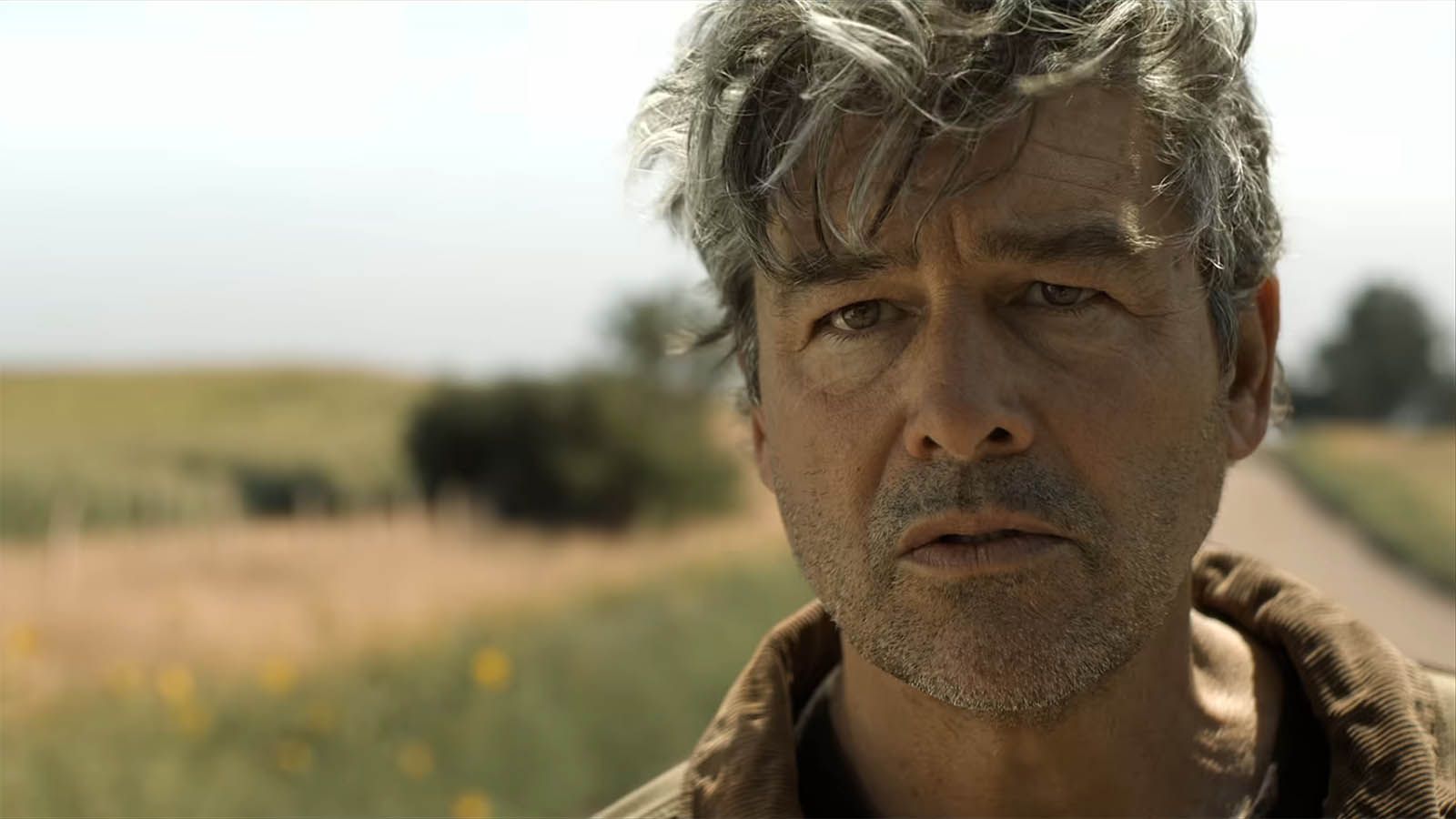 A close up of Kyle Chandler's Hal Jordan standing on a road in the daytime in Lanterns episode 5