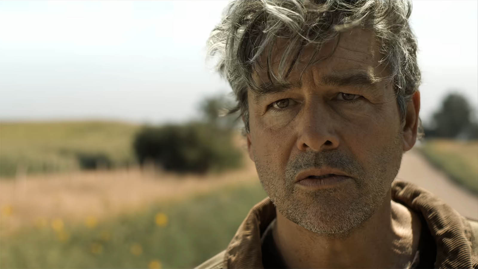 A close up of Kyle Chandler's Hal Jordan standing on a road in the daytime in Lanterns episode 5