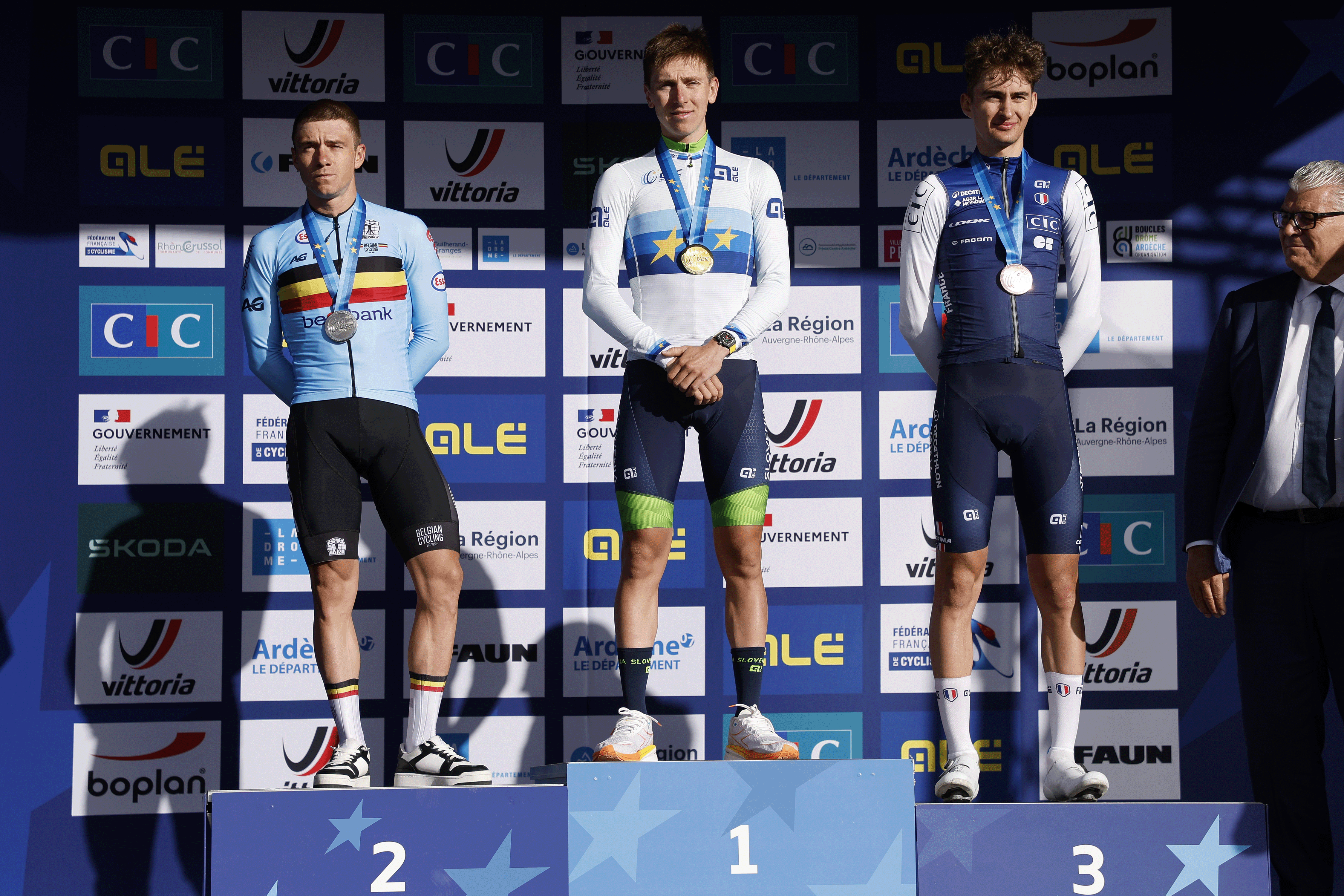 GUILHERAND-GRANGES, FRANCE - OCTOBER 5: Second place and silver medalist Remco Evenepoel of Belgium, winner and gold medalist Tadej Pogacar of Slovenia, third place and bronze medalist Paul Seixas of France during the podium ceremony following the Men's Elite Road Race of the 31st UEC Road Cycling European Championships 2025, a race of 202.5km between Privas and Guilherand-Granges on October 5, 2025 in Guilherand-Granges, France. (Photo by Jean Catuffe/Getty Images)