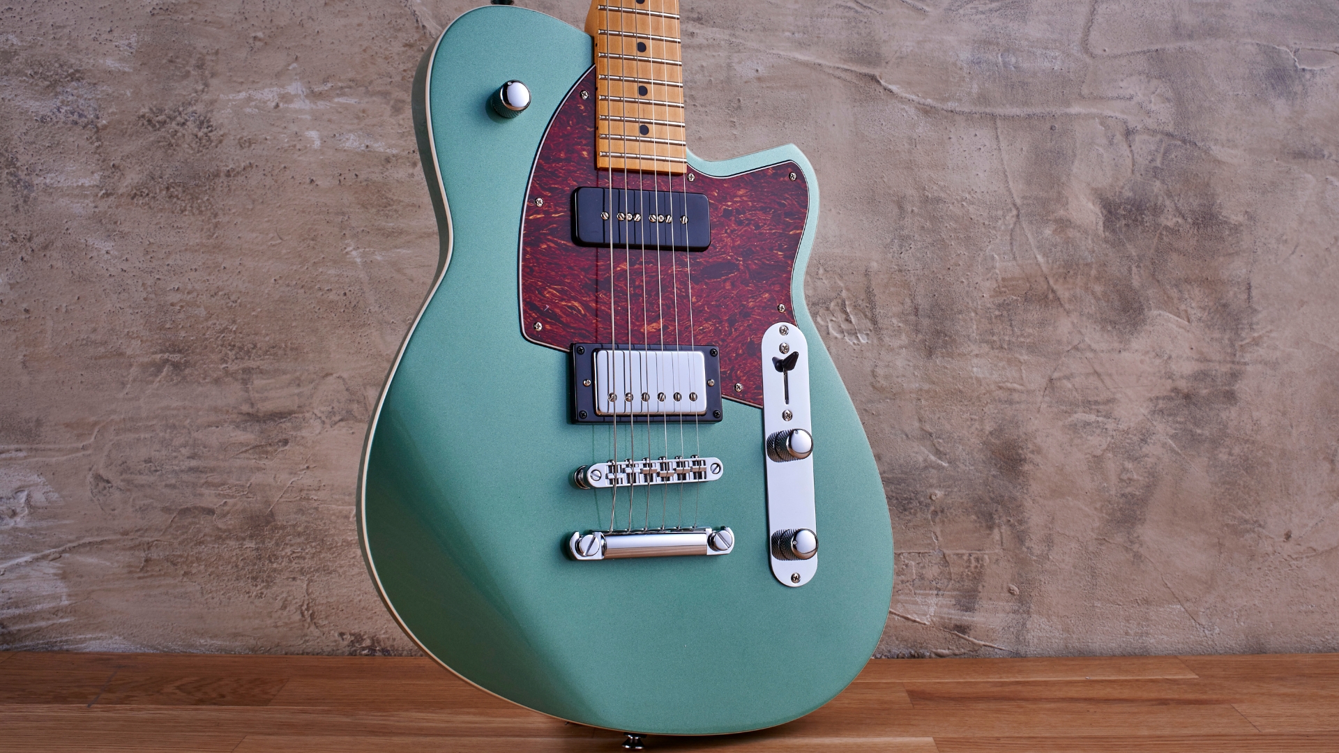 A Reverend Double Agent OG electric guitar leaning against a wall