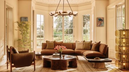 Bright living room with mid-century modern lights, brown sofa, and warm textiles