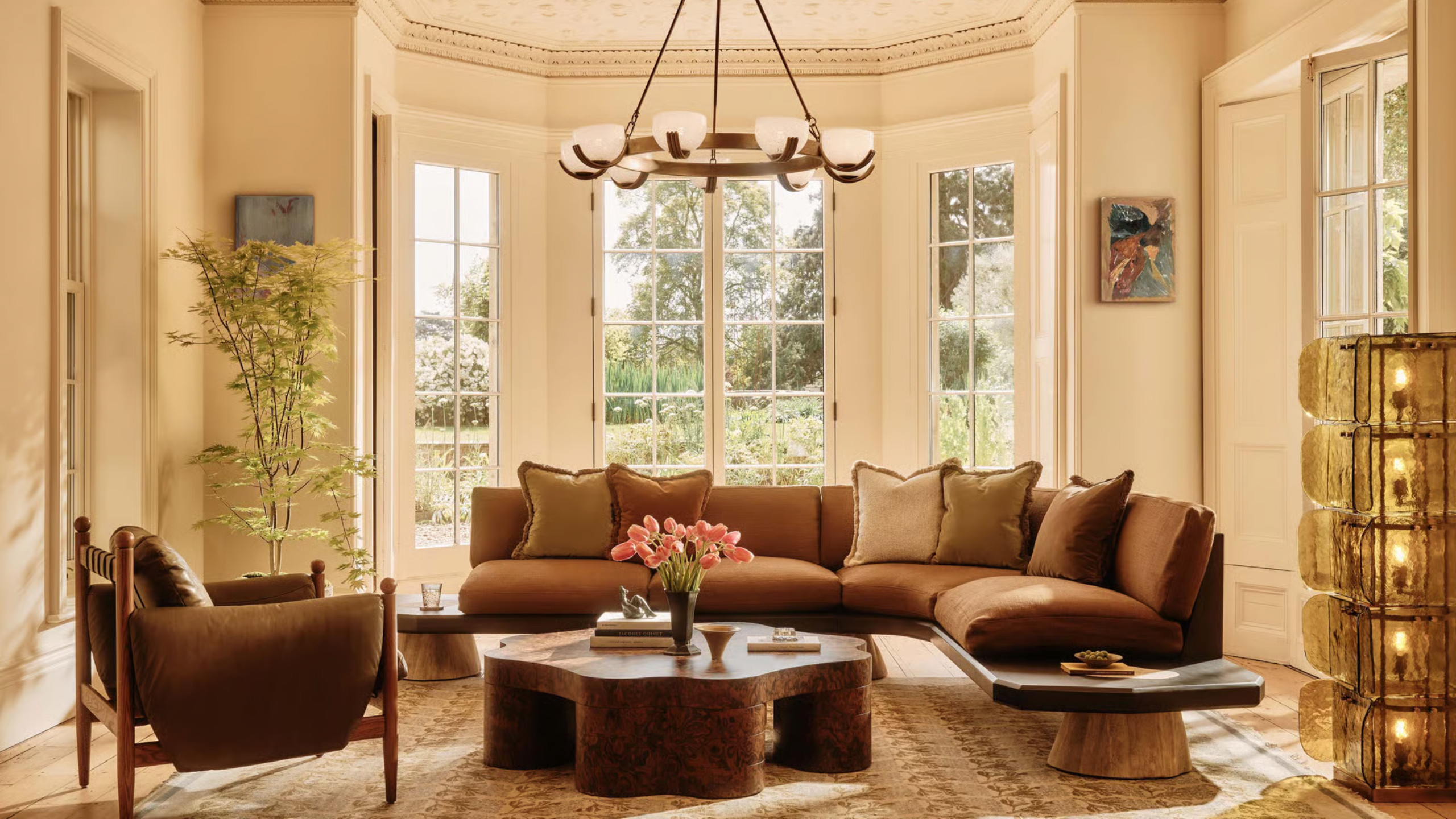 Bright living room with mid-century modern lights, brown sofa, and warm textiles