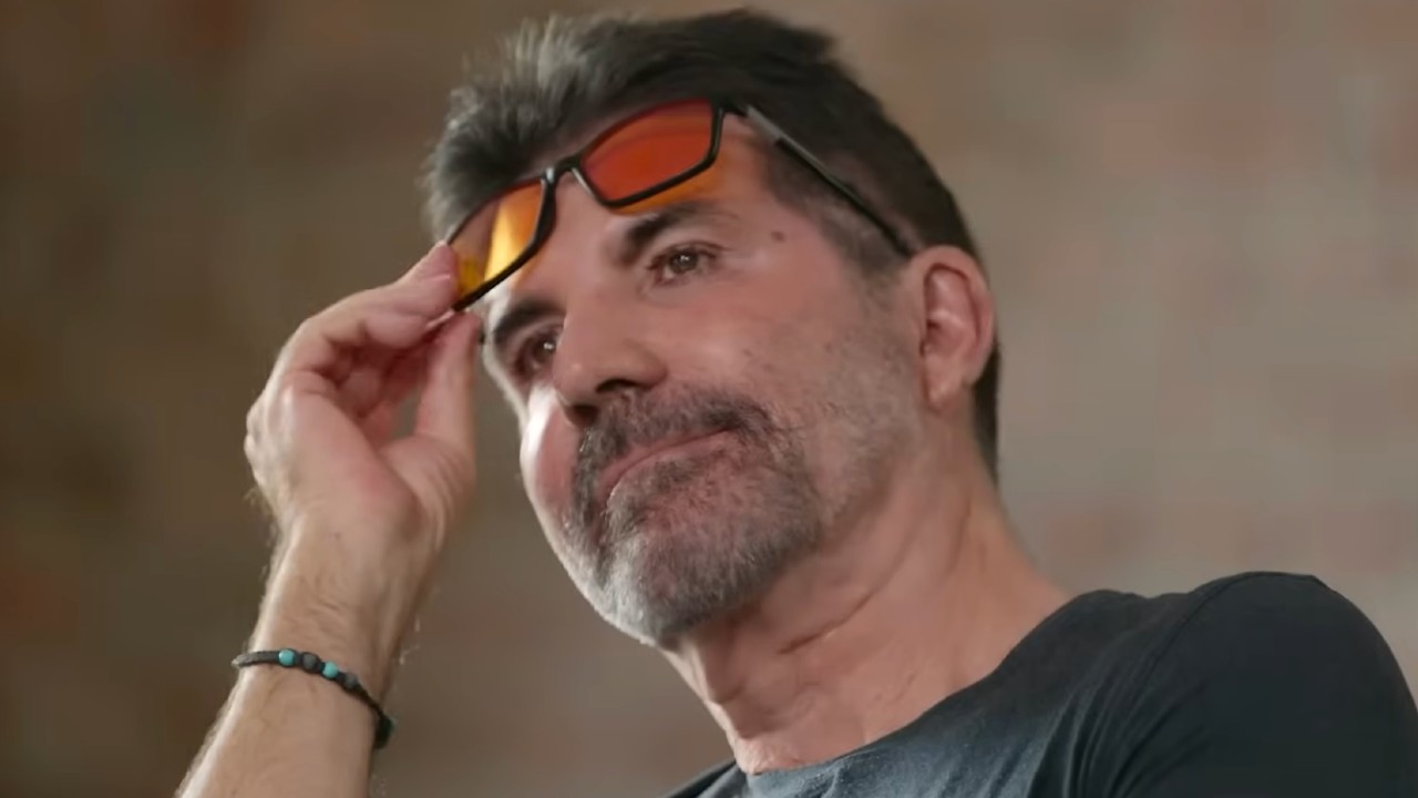 Simon Cowell raising his sunglasses to look at one of the boys auditioning. 