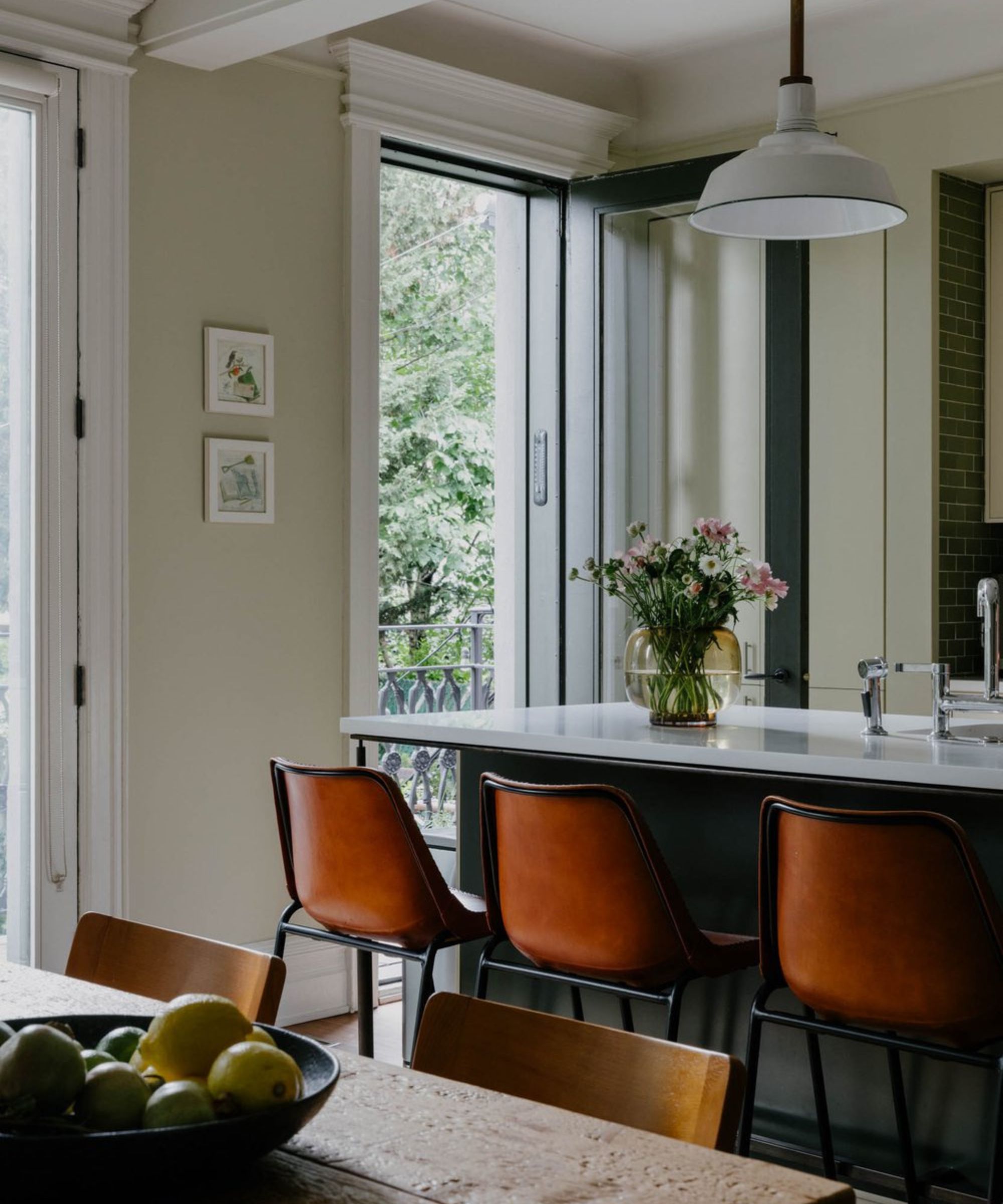 kitchen with sage green walls, kitchen island with tan bar seats and door leading to balcony