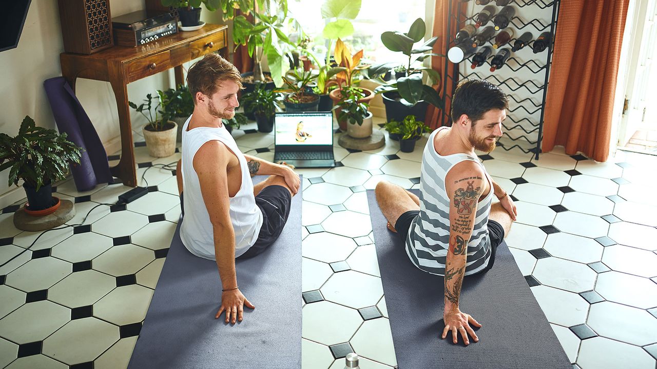 Two men in living room doing a seated twist