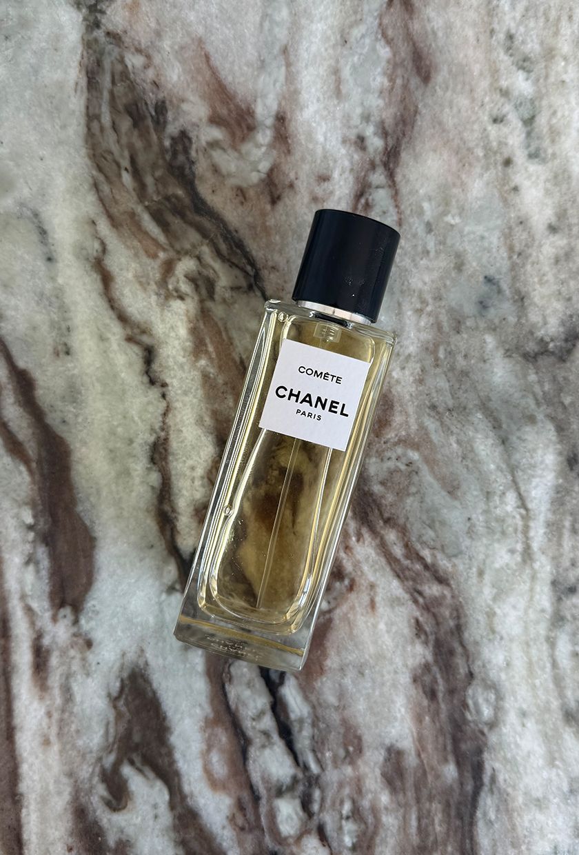 A photo of Chanel Comete perfume on a marble table