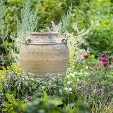 A decorative urn in an herb and flower garden