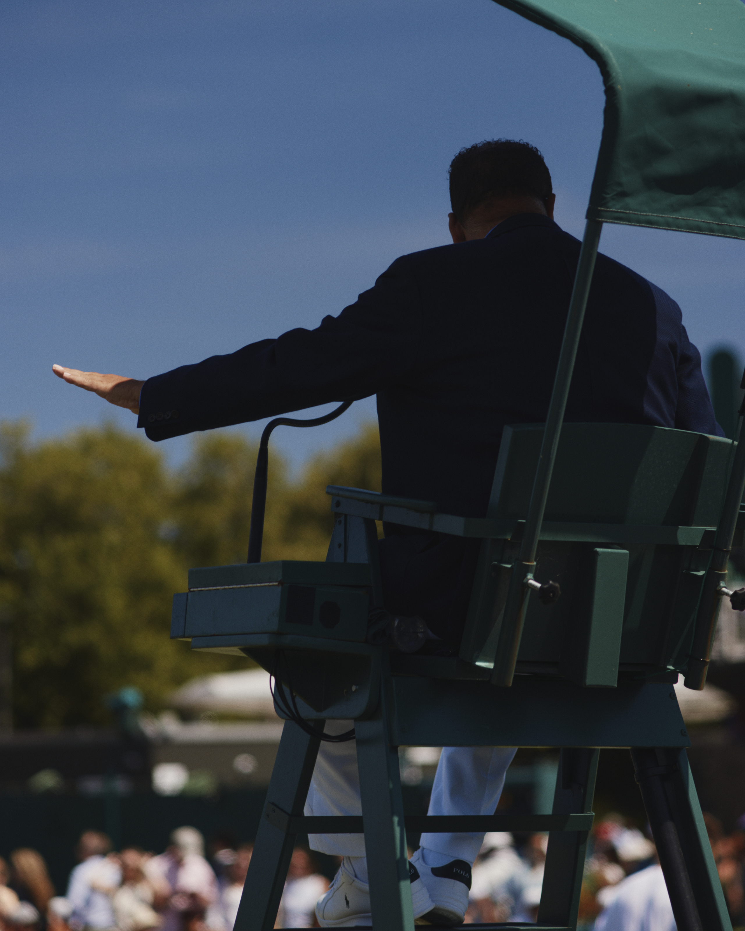 Wimbledon umpire signals with arm, seen from behind