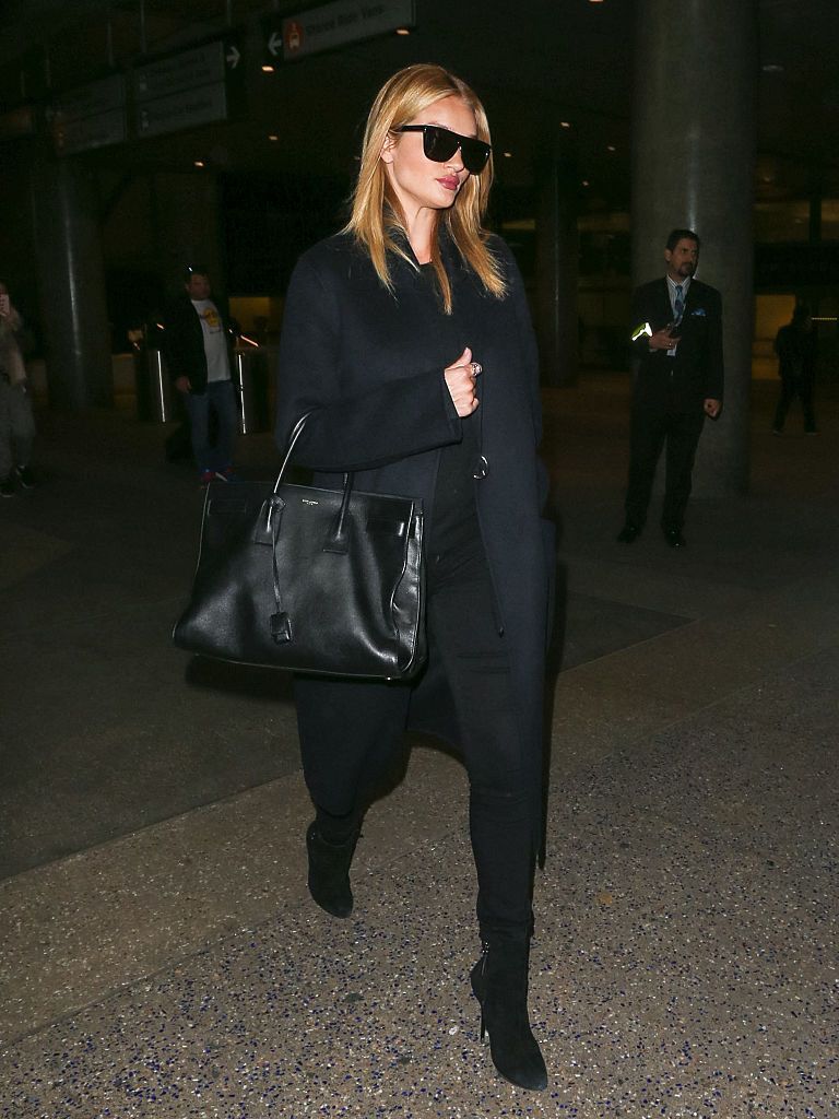 Rosie Huntington-Whiteley wears a black coat, black jeans, black boots and black Saint Laurent bag