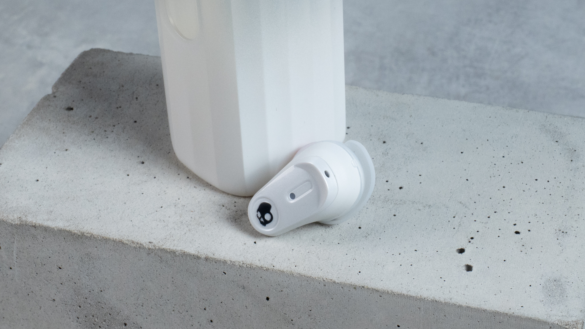 the skullcandy x bose method 360 anc earbuds in white, with a long charging case, a carabiner clip, and various silicone tip sizes