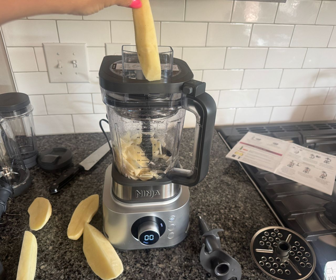 Dropping potato pieces into the Ninja Foodi Power Blender Ultimate System food processor pitcher.