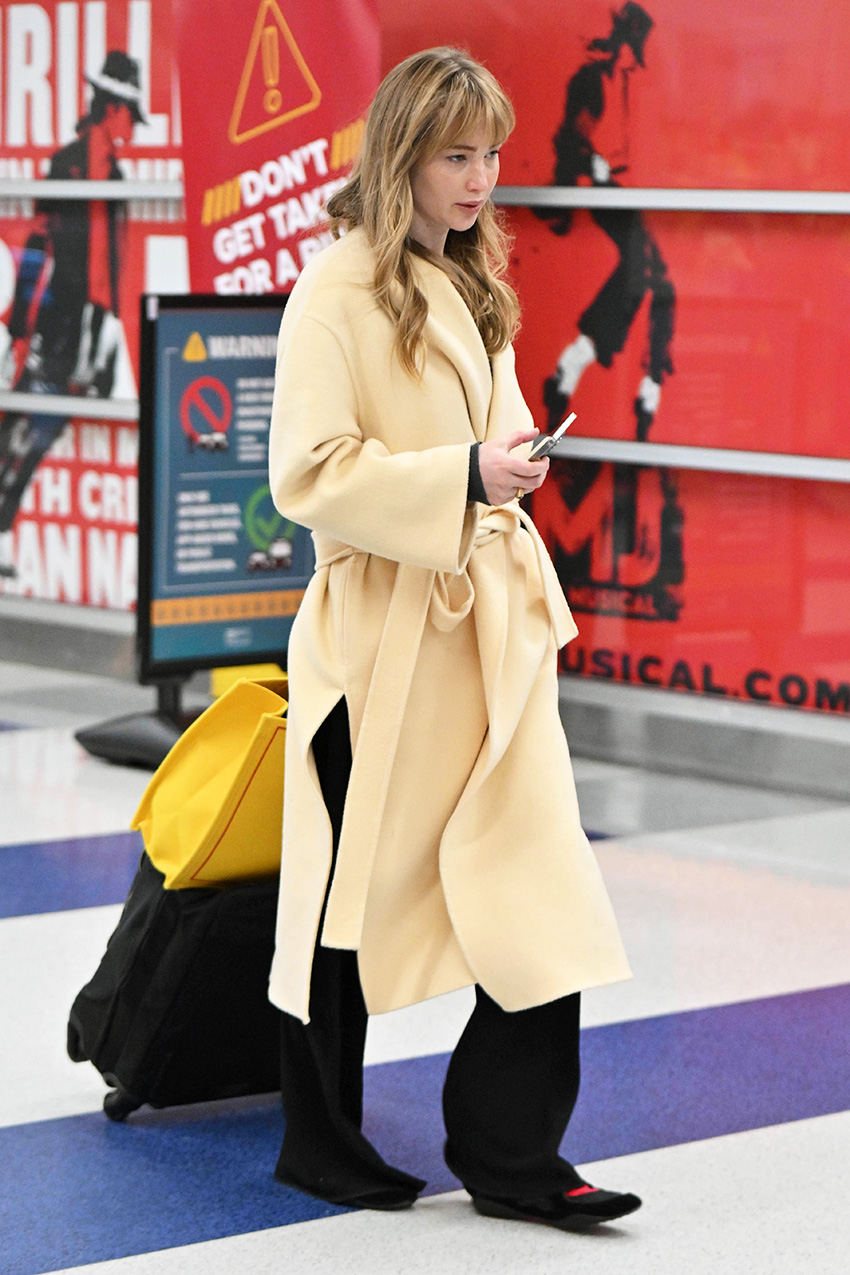 Jennifer Lawrence wearing a yellow coat, black pull-on pants, and Tory Burch Sport Mary Janes