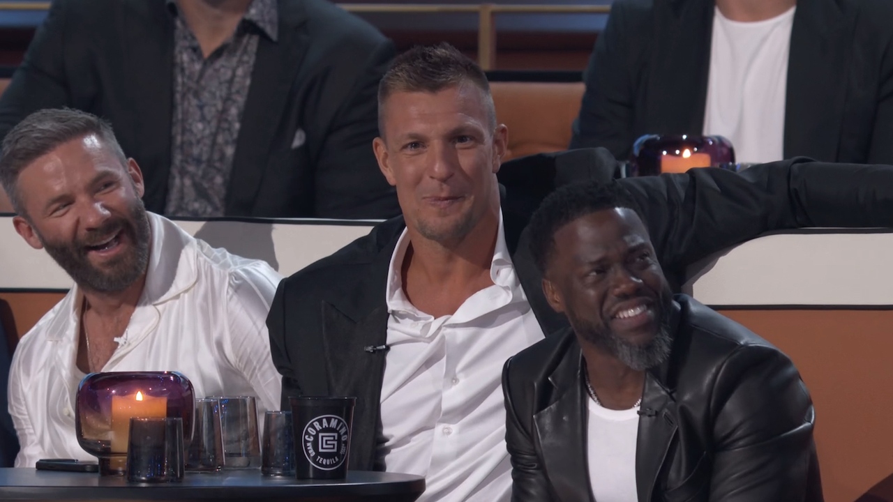Rob Gronkowski looking directly at the camera sitting next to Kevin Hart and Julian Edelman at The Roast of Tom Brady