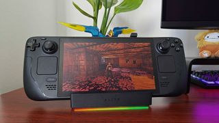 Razer Handheld Dock with Steam Deck OLED sitting on cradle with rainbow RGB lighting on and Tomb Raider Trilogy on screen.