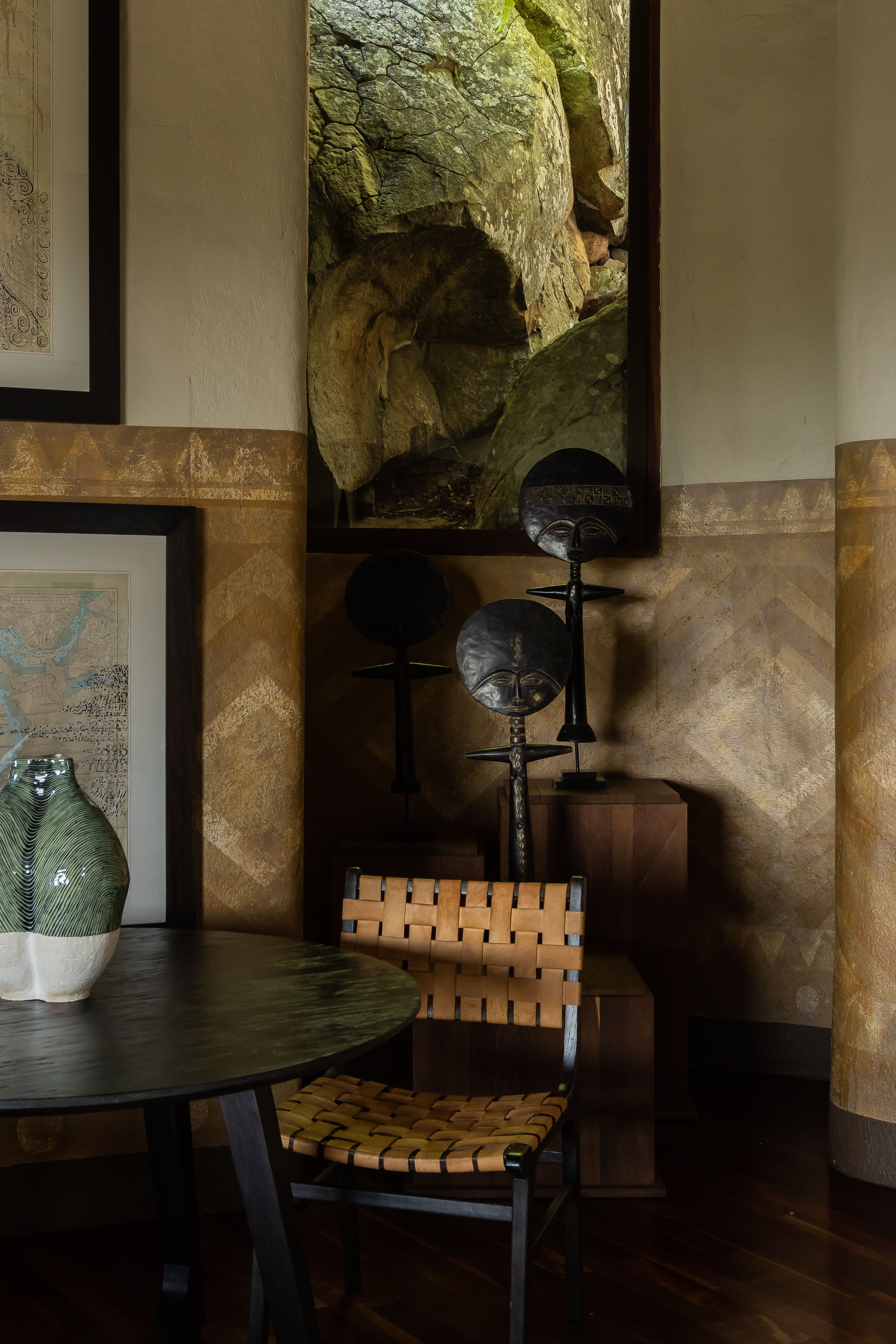 Some artisanal furniture, including wooden chairs with a highly textural, sculptural feel, and a lacquered black table with wood and rattan seats, are portrayed inside a naturally lit hotel room.