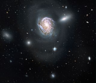 Cosmic Photo Reveals Majestic Spiral Galaxy In Packed Cluster