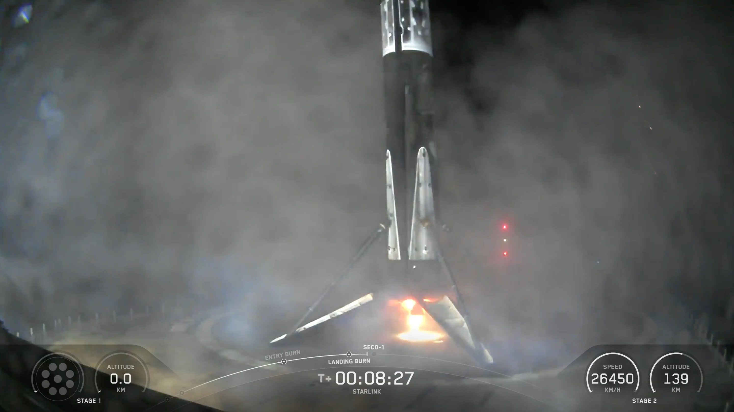 a black and white rocket rests on the deck of a drone ship at night