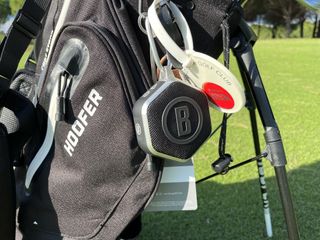 The Bushnell Mini speaker clipped onto the towel hook of a golf bag