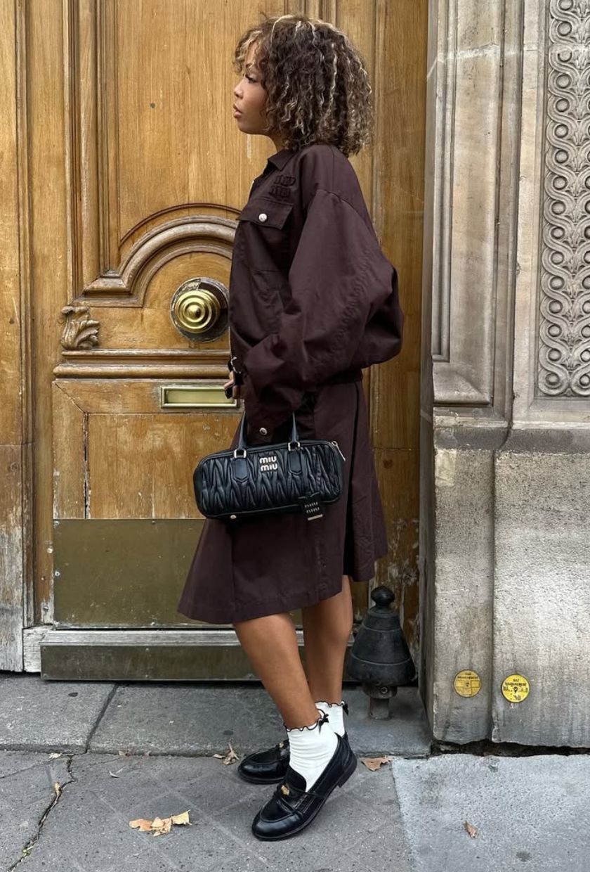 @slipintostyle wears a black Matelass&amp;eacute; Arcadie bag with a brown jacket, midi skirt and black penny loafers