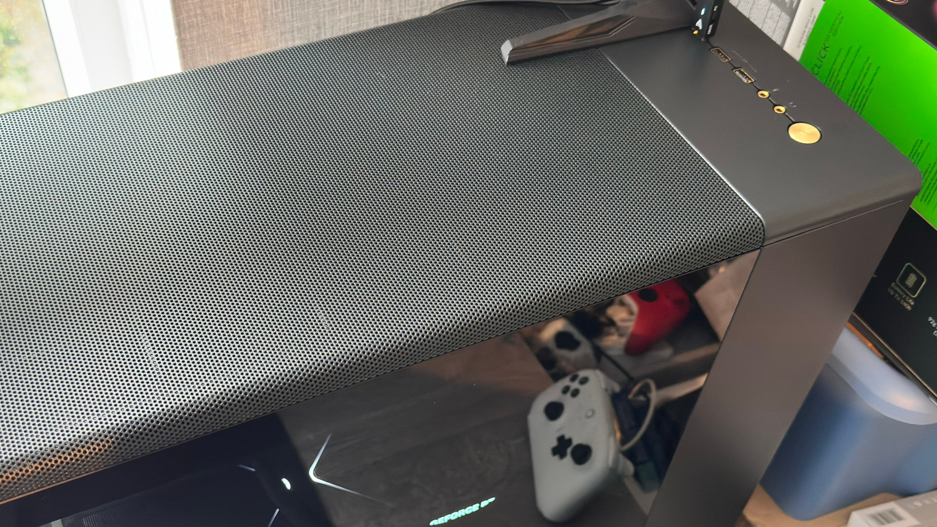 A photo of a Fractal Design North XL PC case, showing the top vented panel and brass power button.