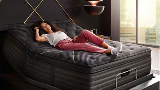 A person reclining on the Beautyrest Black K-Class Plush Pillow Top mattress