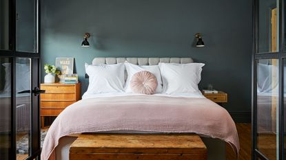 green and pink bedroom with a green rug behind the green headboard and a matching lamp table and lamp and a pink thrown on the bed