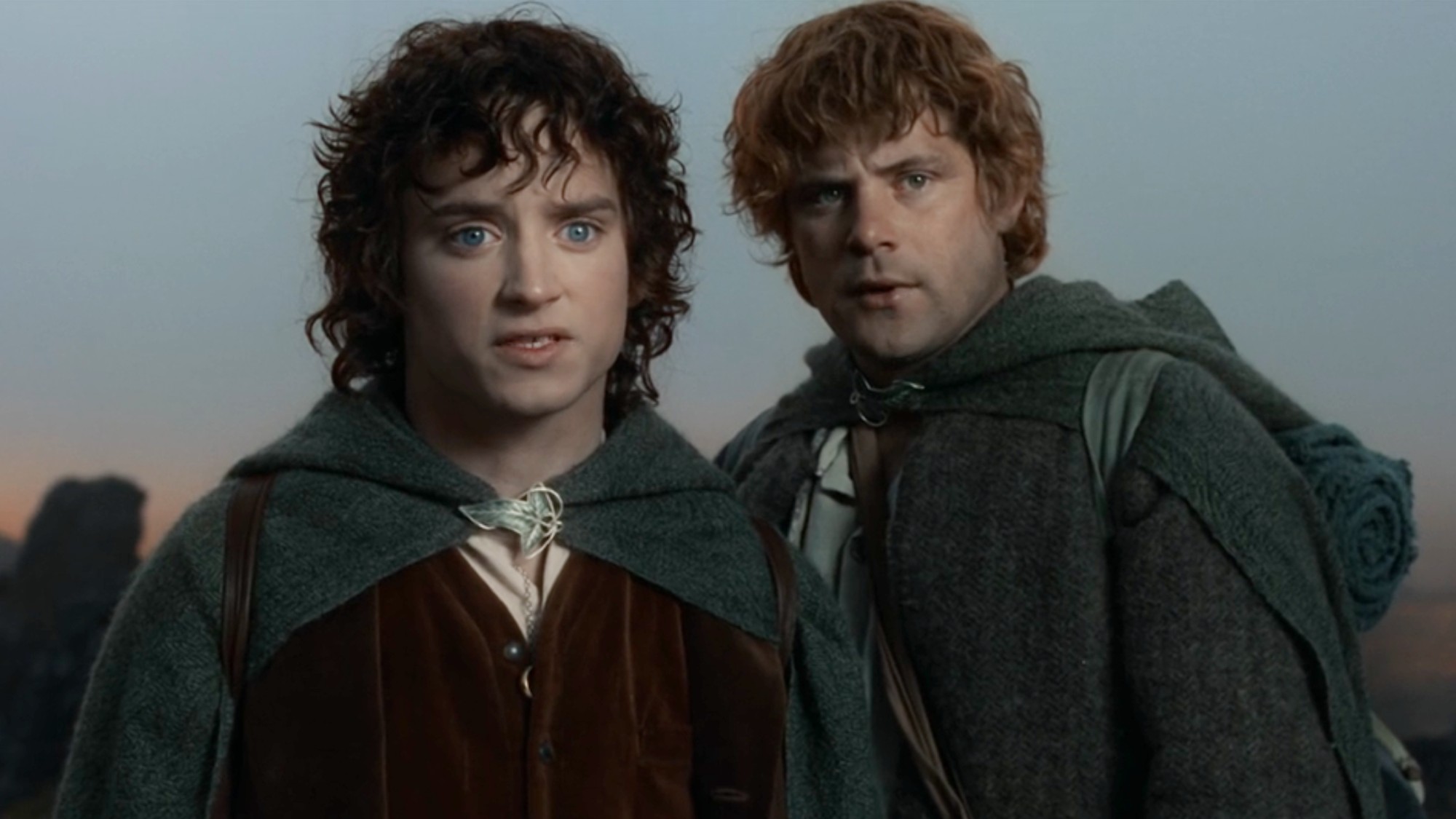 From left to right: Frodo (Elijah Wood) and Sam (Sean Astin) looking forward while standing next to each other in Fellowship of the Ring.