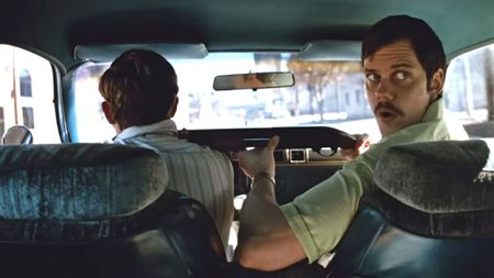 Bill Skarsgard looking forward while Dacre Montgomery drives in Dead Man's Wire