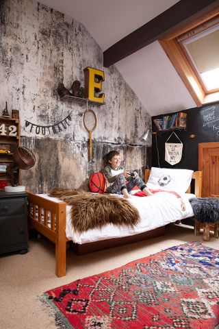 Child's room with industrial style wall mural, wooden bed, footballer bed covers and antique sports equipment used as decoration