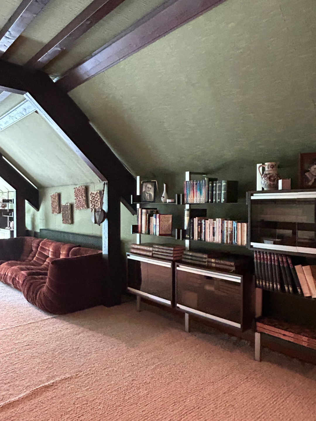 A brown Togo sofa beside built-in shelving and books inside the Roset family&rsquo;s preserved 1970s home.