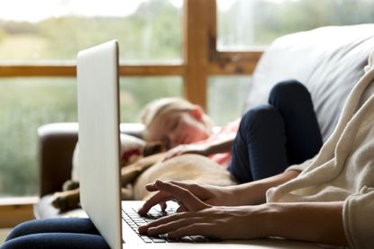 Mother on computer trading bitcoin while daughter sleeps in background