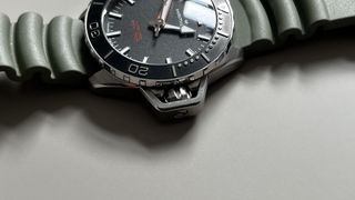 The Hamilton Khaki Navy Frogman with a black dial and a green rubber strap on a grey background