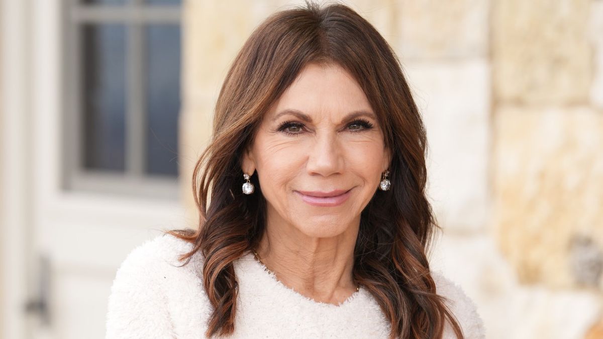 Close-up of Theresa Nist in a white sweater outside of a stone building on The Golden Wedding special as part of The Golden Bachelor.