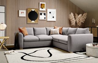 A grey corner sofa in a contemporary living space with wood panelled wall