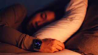 A woman sleeping in a bed wearing an Apple watch that's tracking her sleep