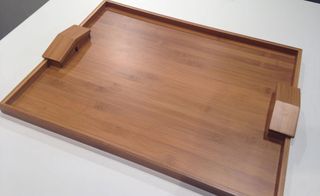 A wooden tray with handles on a white surface.