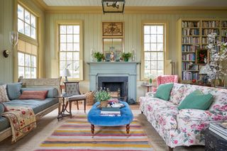 yellow wallpapered living room with blue painted fireplace and patterned sofas eitherside
