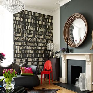 white and grey room with book print wallpaper and circular mirror