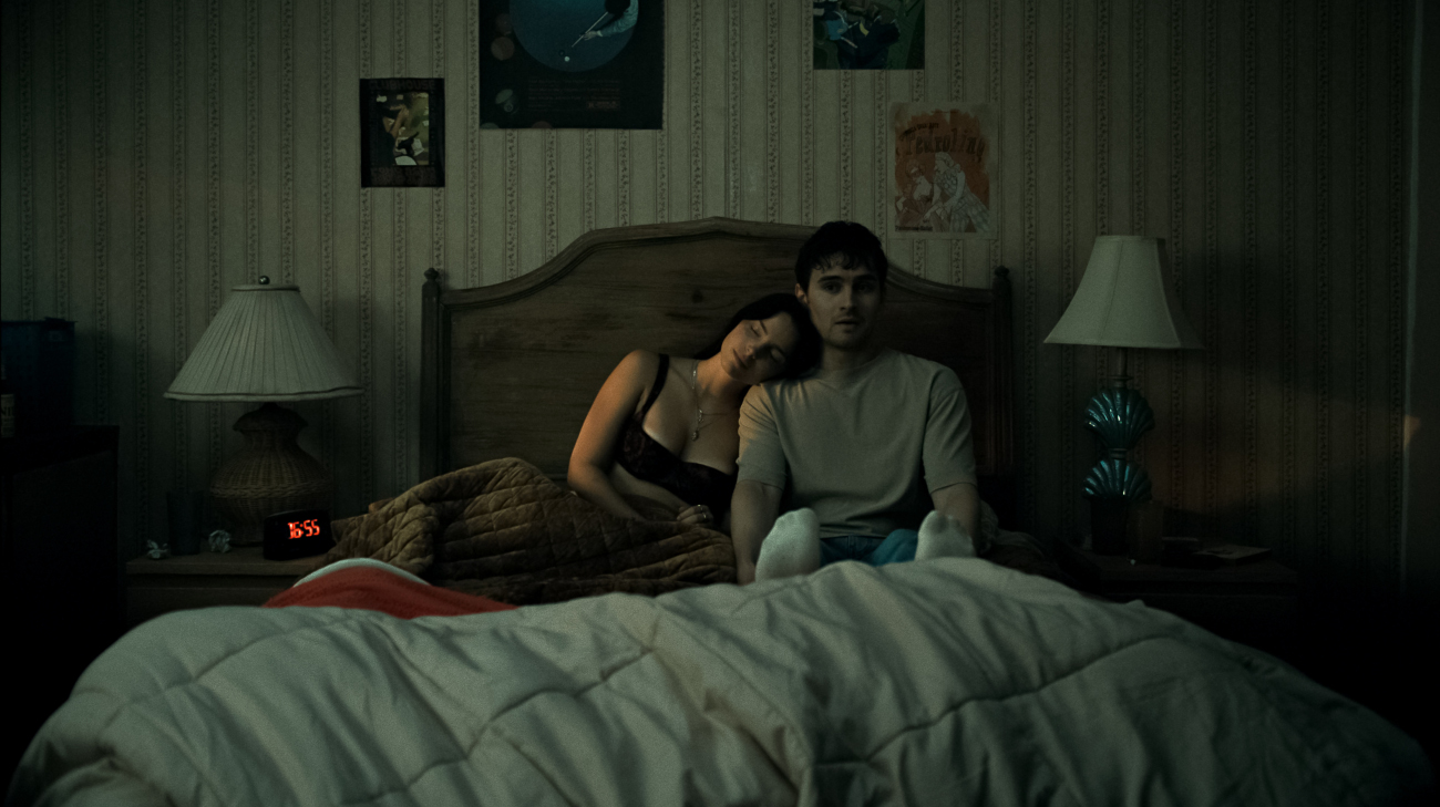 Bear (Michael Johnston) sitting with Nikki (Inde Navarrette) on his bed.
