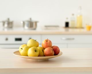 Green and red apples on wooden kitchen countertop