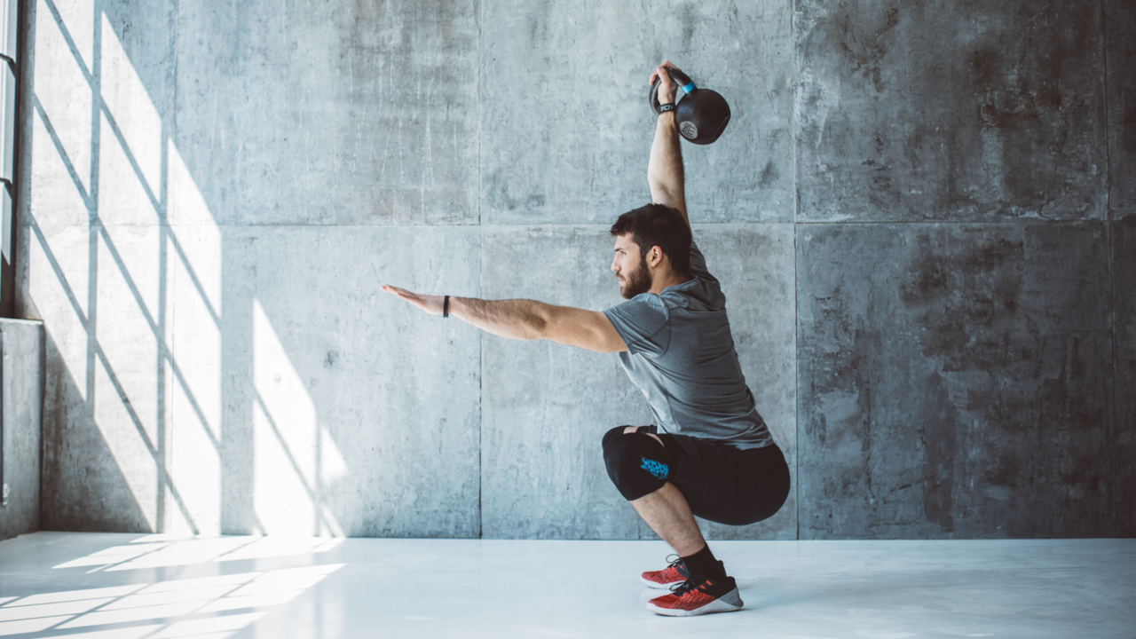 Man doing an overhead kettlebell squat