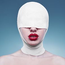 Portrait of young fashion woman with bandaged head wearing red lipstick on bright background