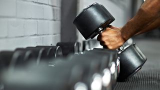 Hands picking up two heavy dumbbells