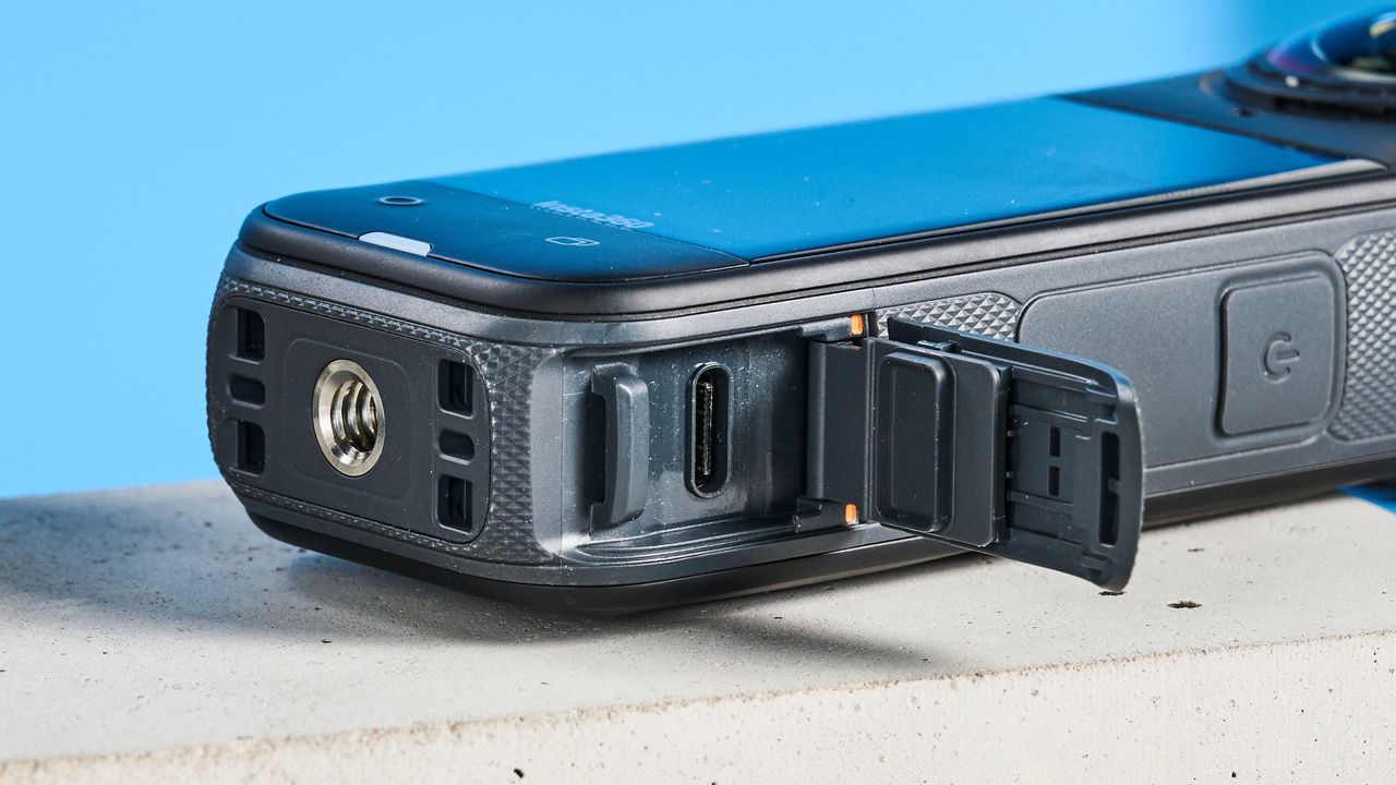 The Insta360 X5 with its USB-C hatch open against a blue background