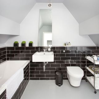 bathroom with black tiles and white fixtures