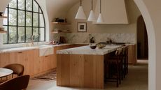 A wooden kitchen with plaster walls and marble countertops